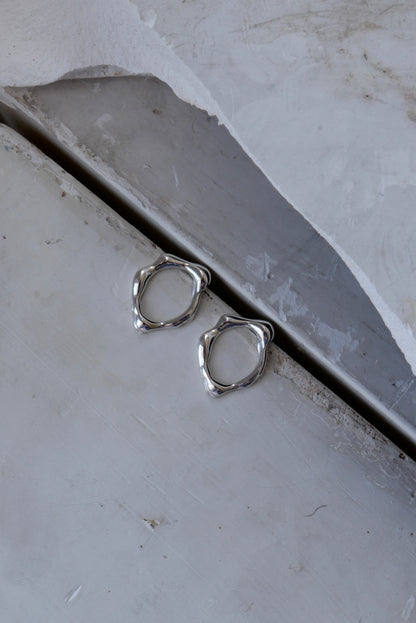 Handcrafted abstract molten silver stud earrings. Made from sustainable recycled silver. Handmade jewellery London jewellery brand Nowhere Soon Studio.